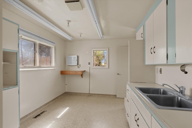 kitchen with visible vents, white cabinets, a sink, and light countertops