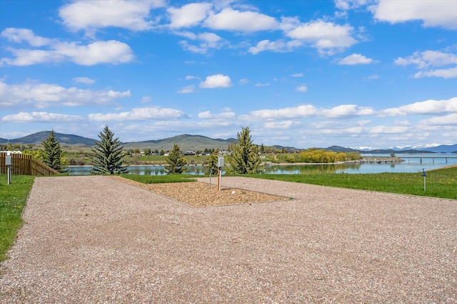 view of community with gravel driveway and a water and mountain view