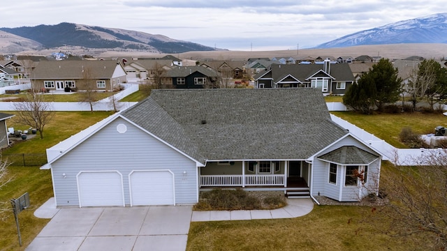 view of front of house with a mountain view, a porch, a garage, and a front lawn