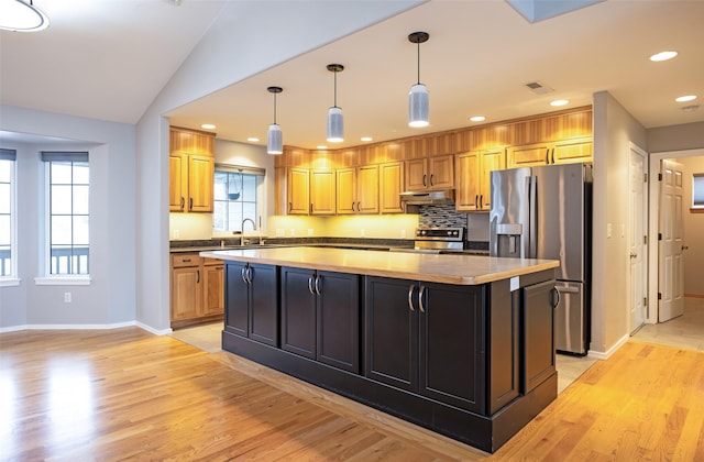 kitchen with appliances with stainless steel finishes, light wood-type flooring, a kitchen island, and a wealth of natural light