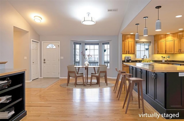 kitchen featuring plenty of natural light, vaulted ceiling, and light hardwood / wood-style flooring