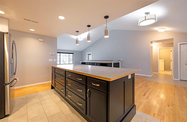 kitchen with stainless steel refrigerator, a center island, light hardwood / wood-style floors, and decorative light fixtures