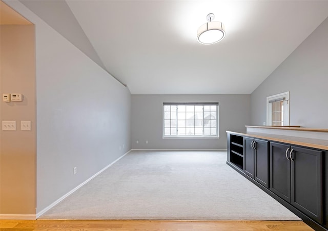 interior space featuring lofted ceiling and light carpet