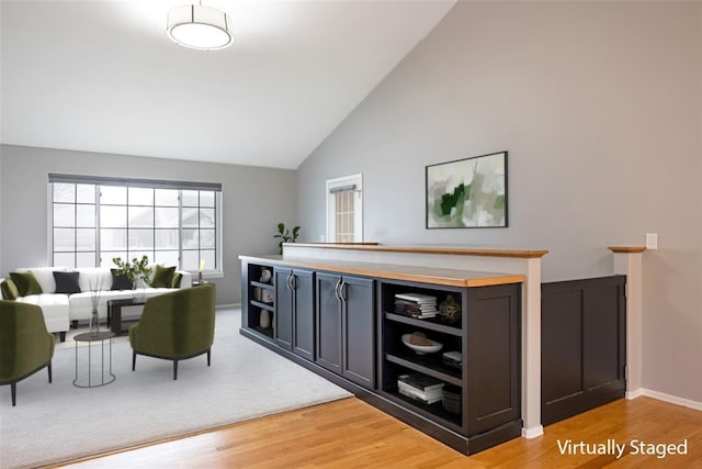 bar featuring high vaulted ceiling and light hardwood / wood-style floors