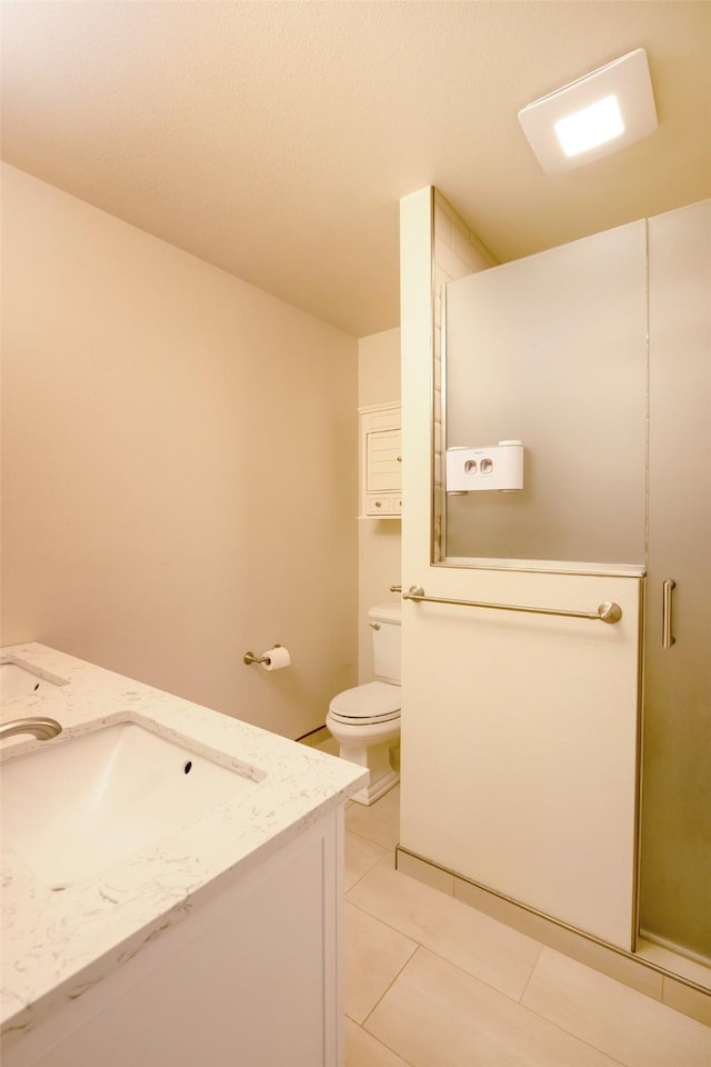 bathroom with tile patterned flooring, vanity, toilet, and a shower with shower door