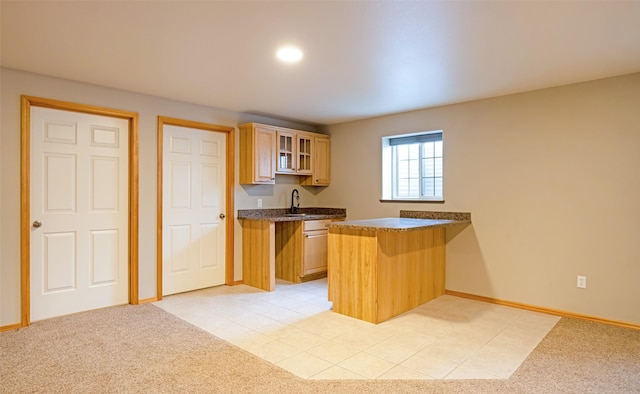 kitchen featuring light brown cabinets, light carpet, sink, kitchen peninsula, and a breakfast bar area