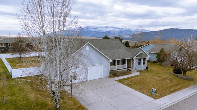 single story home with a mountain view, a front lawn, a porch, and a garage