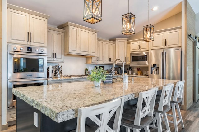 kitchen featuring decorative light fixtures, a breakfast bar, stainless steel appliances, and vaulted ceiling