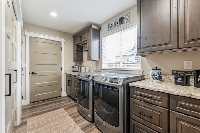 clothes washing area with cabinets, washer and dryer, and hardwood / wood-style flooring