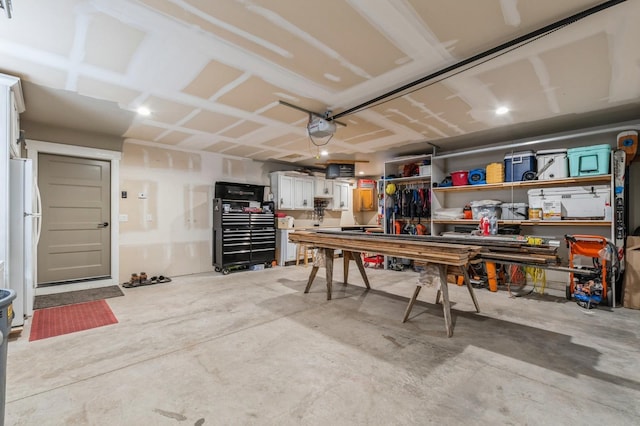 garage with a workshop area, a garage door opener, and white refrigerator