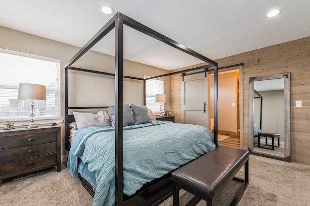 carpeted bedroom featuring wood walls and a barn door