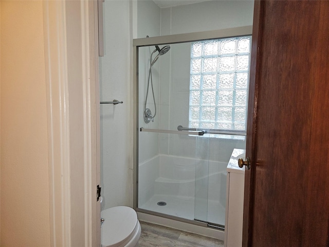 bathroom featuring wood-type flooring, toilet, and an enclosed shower