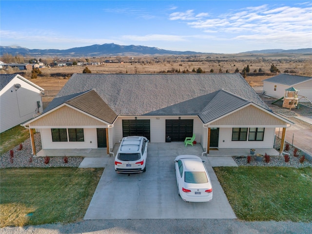 ranch-style home featuring a mountain view, a garage, and a front lawn