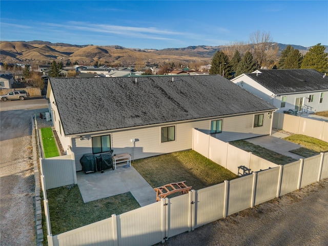 back of house with a mountain view, a yard, and a patio area