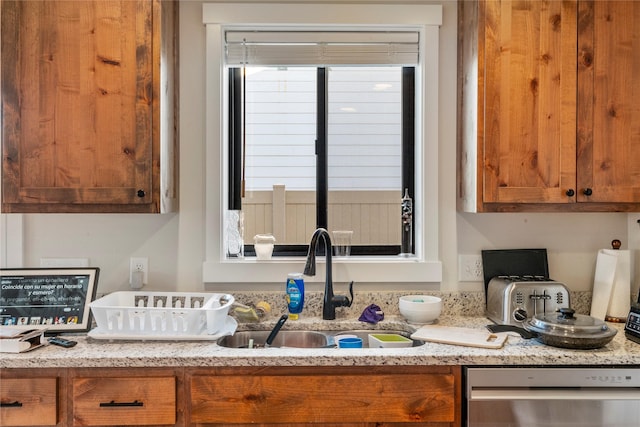 kitchen featuring light stone counters, dishwasher, and sink