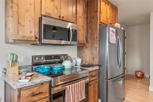 703 S Oak St Unit 1 & 2, Townsend, MT 59644 - kitchen with stainless steel appliances, light wood-style flooring, brown cabinetry, and light stone counters