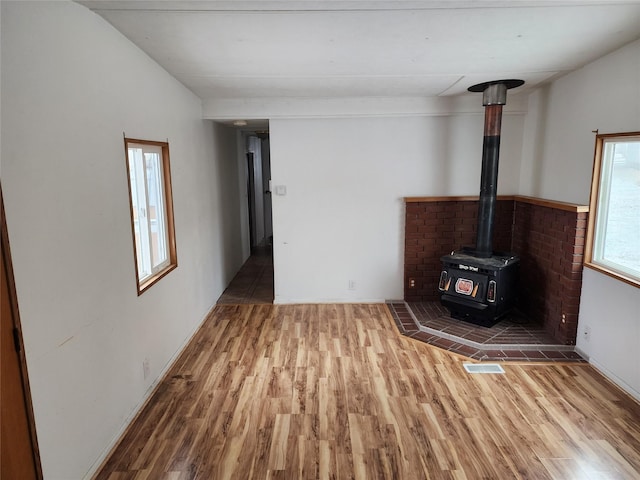 unfurnished living room featuring visible vents, wood finished floors, and a wood stove