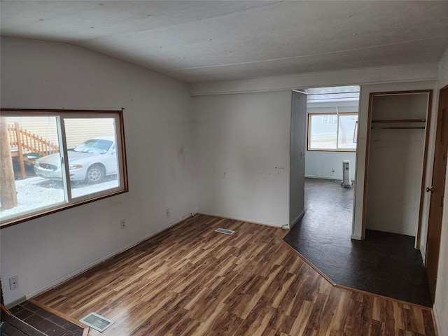 interior space with vaulted ceiling, dark wood-style flooring, and visible vents