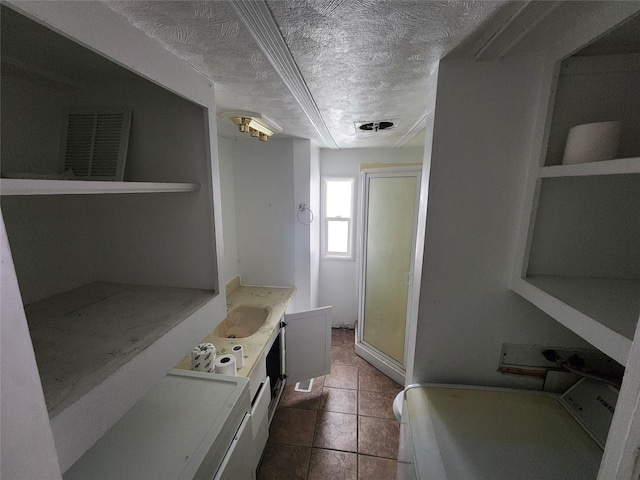 clothes washing area featuring a sink, a textured ceiling, and tile patterned floors