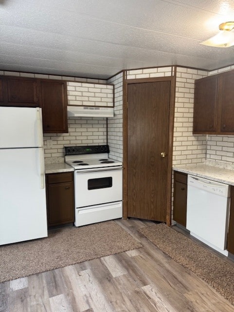 kitchen with dark brown cabinets, white appliances, and light hardwood / wood-style floors