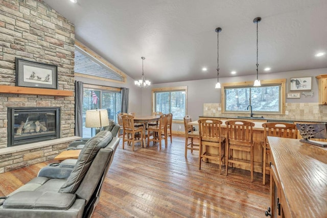 living room featuring lofted ceiling, sink, light hardwood / wood-style flooring, a fireplace, and a notable chandelier