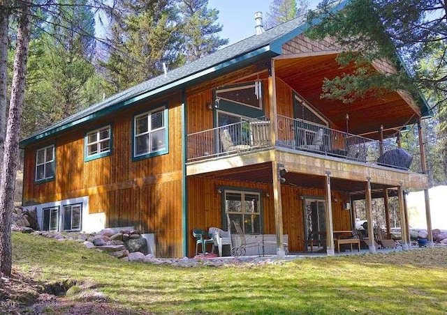 rear view of property featuring a lawn, a patio area, and a balcony