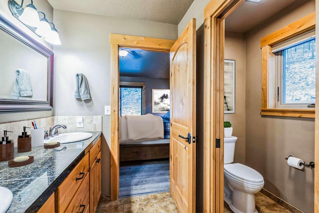 bathroom featuring a textured ceiling, vanity, toilet, and a wealth of natural light