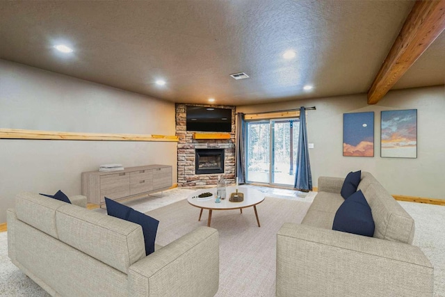 living room featuring a textured ceiling, a stone fireplace, and light carpet