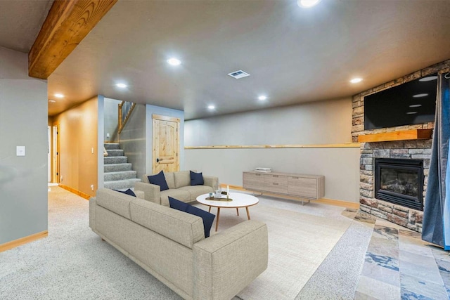 carpeted living room featuring beam ceiling and a stone fireplace