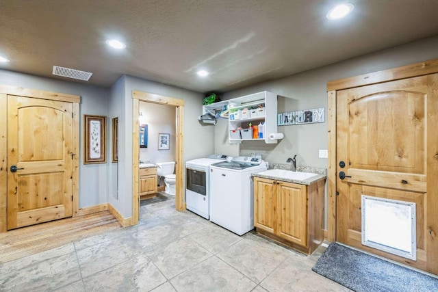 washroom featuring cabinets, sink, and washing machine and clothes dryer