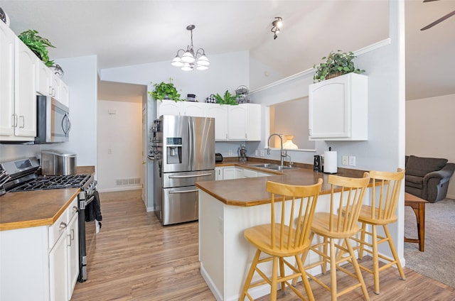 kitchen with white cabinetry, sink, kitchen peninsula, a breakfast bar area, and appliances with stainless steel finishes