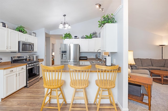 kitchen with a breakfast bar area, white cabinetry, a chandelier, and stainless steel appliances