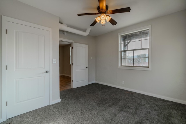 unfurnished bedroom with dark colored carpet and ceiling fan