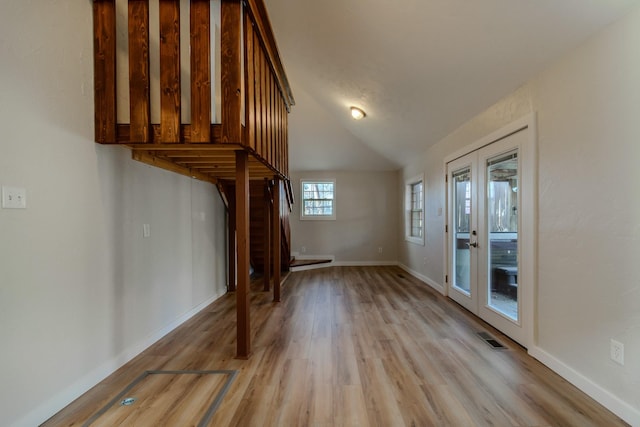 unfurnished living room featuring french doors, light hardwood / wood-style floors, and lofted ceiling