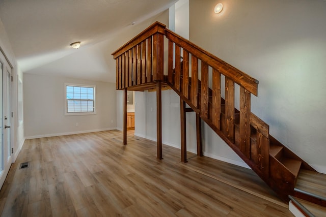 stairway with hardwood / wood-style floors and lofted ceiling