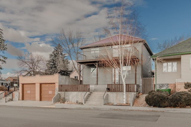 view of front facade with a balcony, a garage, and an outdoor structure