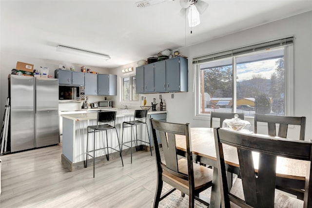 kitchen featuring blue cabinets, light hardwood / wood-style flooring, ceiling fan, kitchen peninsula, and stainless steel appliances