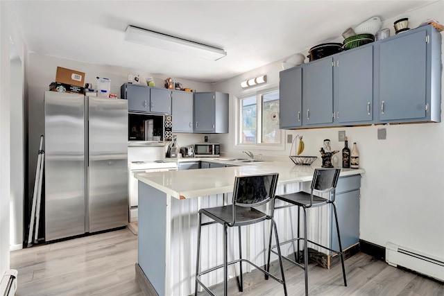 kitchen with a baseboard heating unit, kitchen peninsula, light hardwood / wood-style floors, a breakfast bar, and appliances with stainless steel finishes