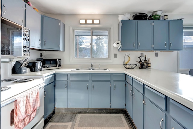 kitchen with blue cabinetry, electric range, and sink