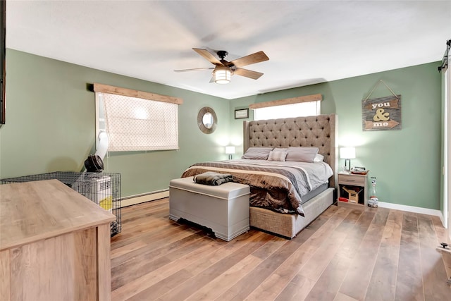 bedroom featuring ceiling fan, a baseboard heating unit, and light hardwood / wood-style flooring