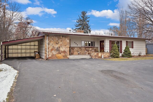 444 S Meridian Rd, Kalispell, MT 59901 - single story home featuring stone siding, a chimney, asphalt driveway, and a detached carport