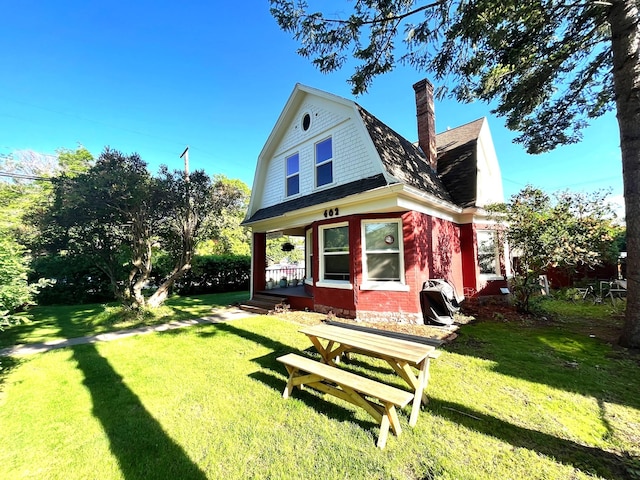 rear view of house featuring a porch and a lawn