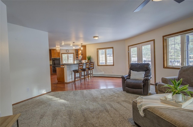 living room featuring a wealth of natural light, ceiling fan, light hardwood / wood-style floors, and a baseboard radiator