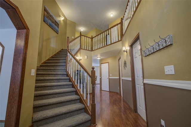 stairway featuring a towering ceiling and wood-type flooring