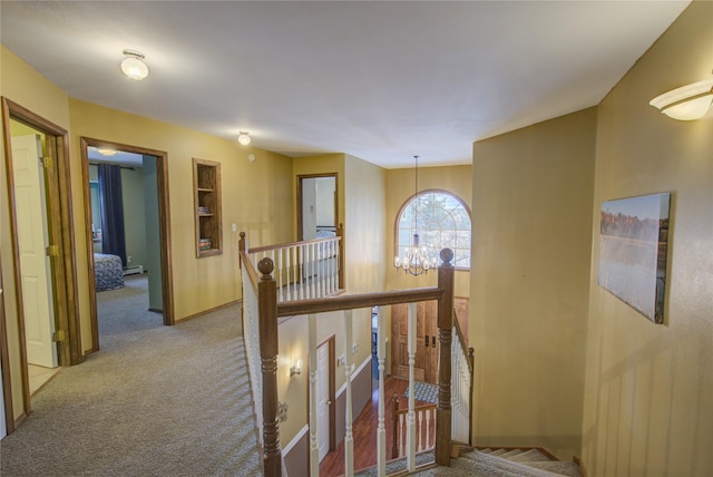 hall featuring carpet flooring, baseboard heating, and an inviting chandelier