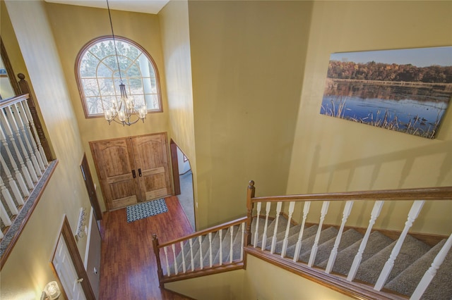 foyer entrance featuring a chandelier, a towering ceiling, and dark wood-type flooring