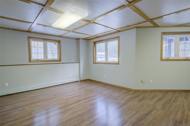 unfurnished room with a healthy amount of sunlight, a baseboard heating unit, and hardwood / wood-style flooring