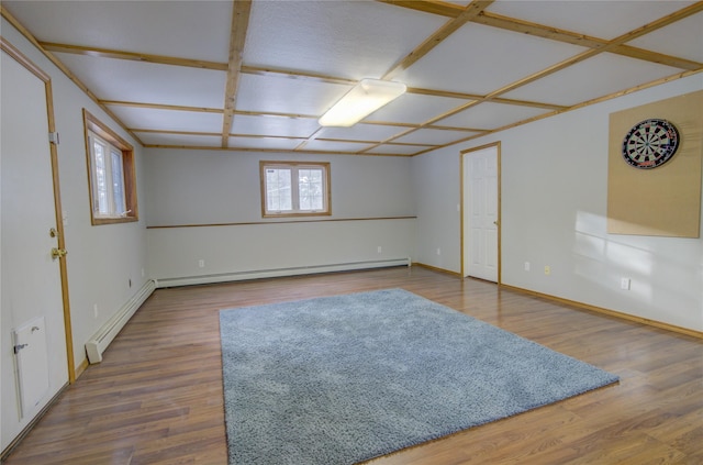 empty room featuring wood-type flooring, coffered ceiling, and a baseboard heating unit