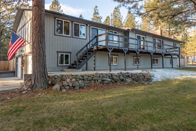 rear view of property featuring a garage, a yard, and a deck