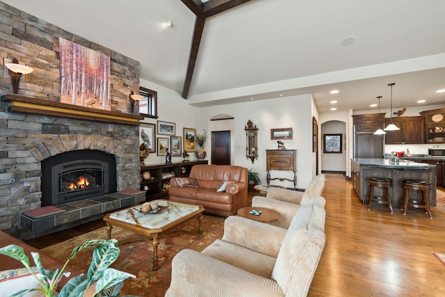 living room with lofted ceiling with beams, a fireplace, and light hardwood / wood-style flooring